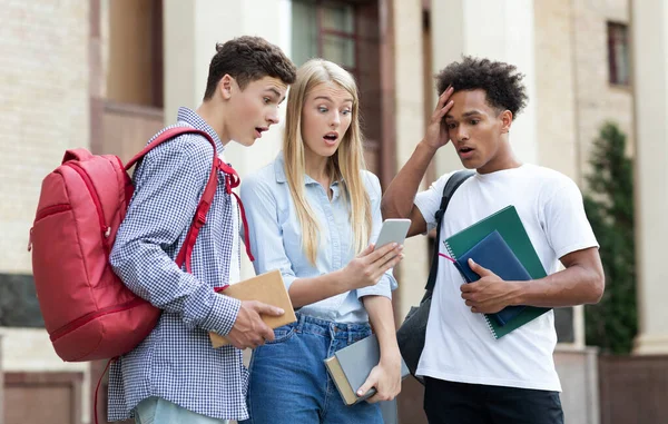 Shocked classmates checking exam results on smartphone
