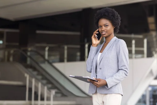 African American businesswoman talking on cell phone near office building