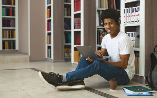 Afro estudante ouvir música enquanto estuda, sentado no chão — Fotografia de Stock