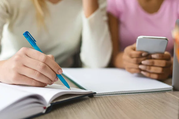 Chica adolescente escribiendo notas en cuaderno, estudiando con amigos al aire libre —  Fotos de Stock