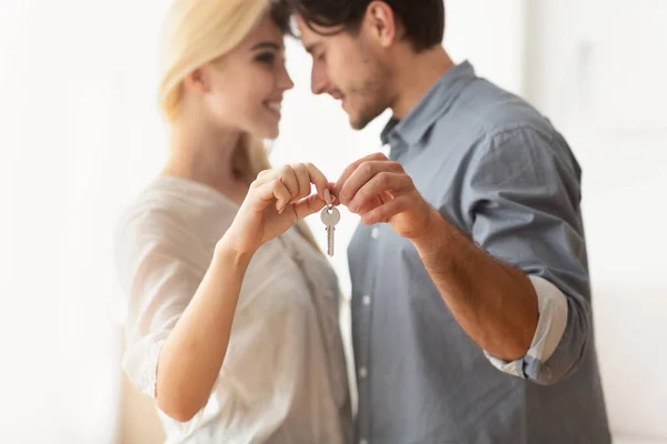 Муж и жена держат новый плоский ключ и обнимаются в помещении — стоковое фото