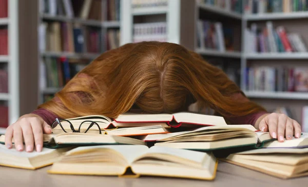 Fáradt vörös hajú lány alszik könyvek campus könyvtár — Stock Fotó