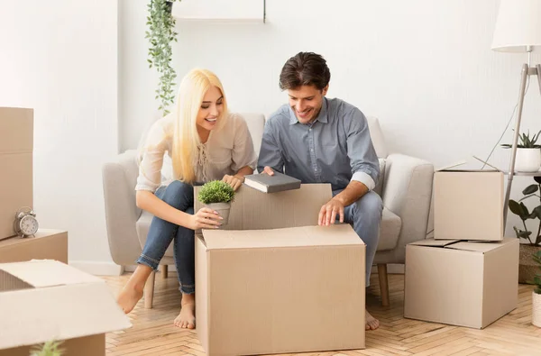 Young man and woman packing things in moving boxes indoor