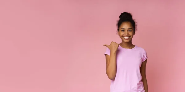 Vacker afrikansk flicka pekar på kopiera utrymme med tummen — Stockfoto