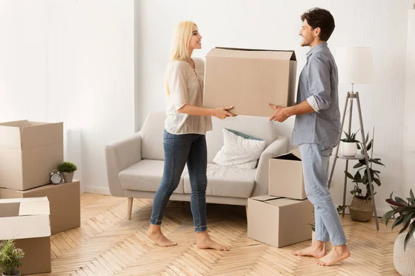 Муж и жена вместе несут коробку для переезда в новую квартиру — стоковое фото