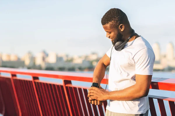 Athletic black guy looking at his smartwatch — Stock Photo, Image