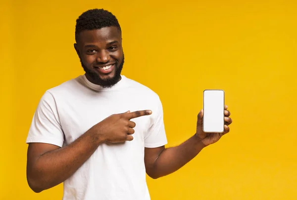 Usmívající se africký Američan ukazuje na mobil s prázdnou obrazovkou — Stock fotografie