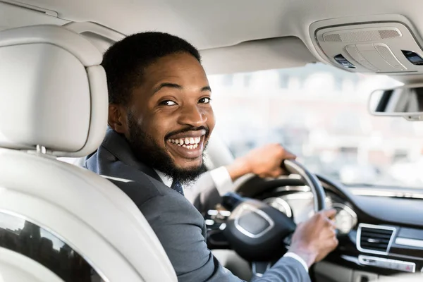 Giovane uomo d'affari afro al posto di guida sorridente alla macchina fotografica — Foto Stock