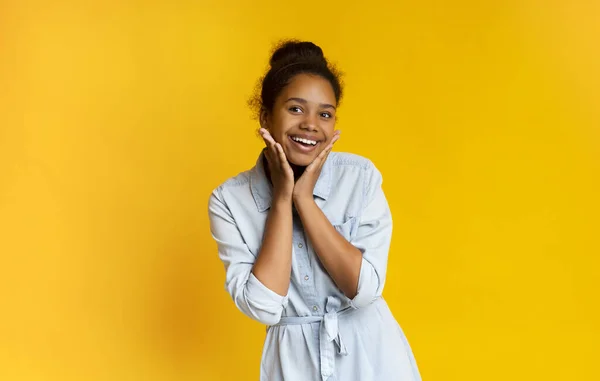 Excited black schoolgirl smiling on camera and touching her face — Stock Photo, Image