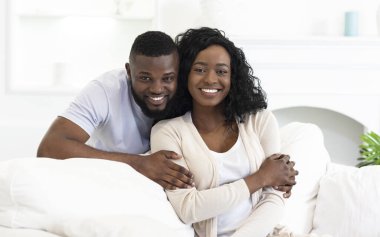 Afro-Amerikan ailesi evde oturmuş kameraya poz veriyor.
