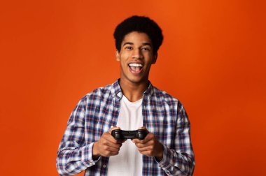 Excited african guy holding joystick and playing video games