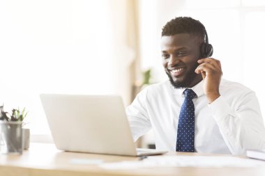 Bilgisayara bakan kulaklıklı mutlu bir danışman.