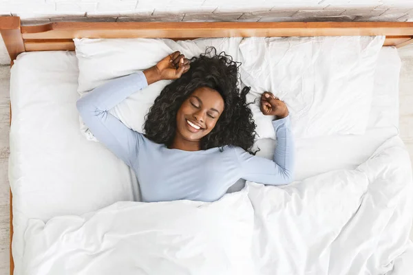 Top view of smiling woman stretching in bed — Stock Photo, Image