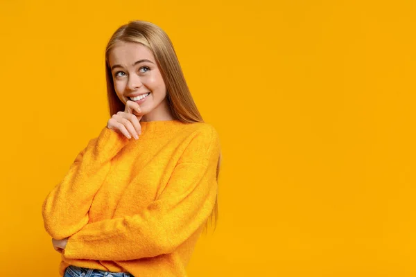Pensive teen girl looking upwards on orange studio background — Stock Photo, Image