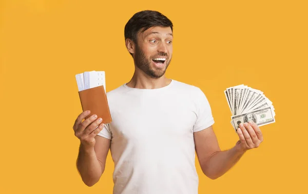 Man Holding Money, Tickets And Passport On Yellow Background