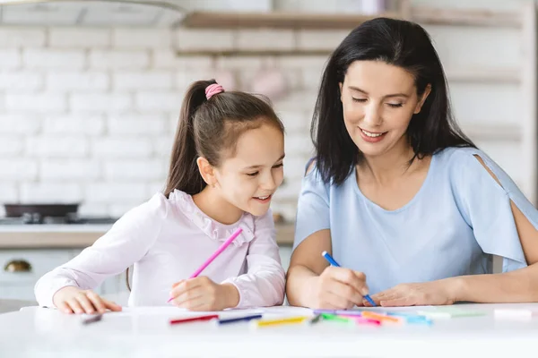 Милая маленькая девочка рисует вместе со своей мамой на кухне — стоковое фото