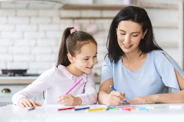 Petite fille mignonne dessinant avec sa mère dans la cuisine — Photo