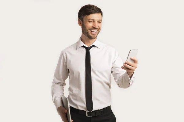 ผู้ชายที่ยิ้มใช้โทรศัพท์มือถือแท็บเล็ตยืนในสตูดิโอ — ภาพถ่ายสต็อก