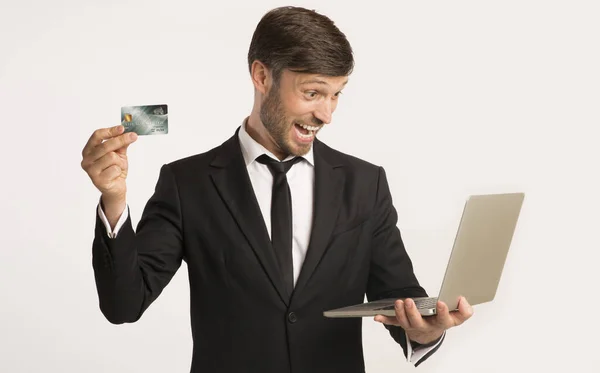Nadšený podnikatel držící kreditní kartu a notebook, Studio Shot — Stock fotografie