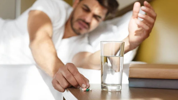 Fiatal keleti férfi gyógyszert szed az ágyban, hányinger — Stock Fotó