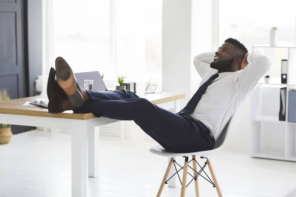 Joven gerente alegre relajándose en la silla en la oficina moderna blanca —  Fotos de Stock