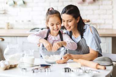 Küçük kız annelerle pasta pişirmeyi öğreniyor.