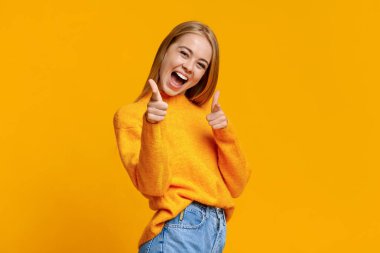 Neşeli genç kız işaret parmağıyla kamerayı işaret ediyor.