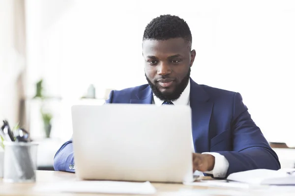 Hombre negro trabajador escribiendo en el ordenador portátil en la oficina — Foto de Stock