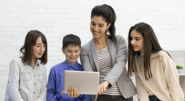 Вчитель і діти, які дивляться на планшетний комп'ютер під час перерви — стокове фото