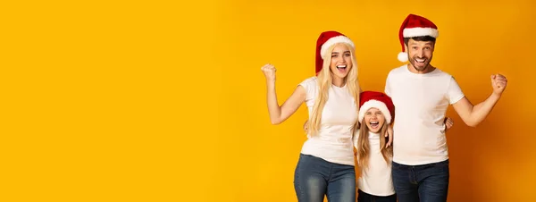 Parents And Daughter In Santa Hats Shaking Fists In Studio, Panorama — ストック写真