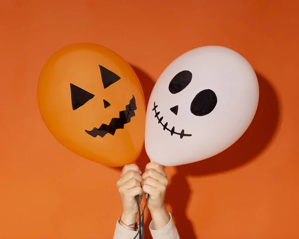 Globos de Halloween con caras divertidas en manos de mujer —  Fotos de Stock