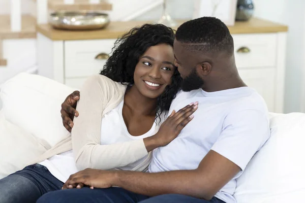 Romantic black couple cuddling, relaxing on couch at home — ストック写真