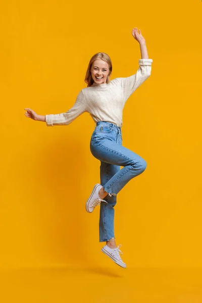 Gelukkig tiener meisje having plezier, springen op oranje studio achtergrond — Stockfoto