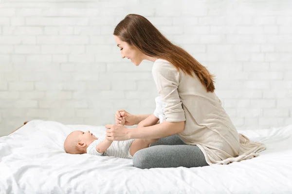 Ung mor leker med sitt nyfödda barn hemma — Stockfoto