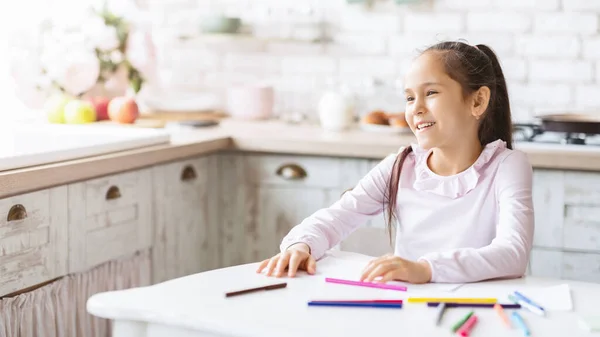 Entzückendes kleines Mädchen sitzt am Küchentisch und lächelt — Stockfoto