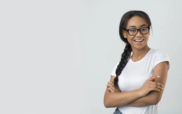 Excited student girl in eyeglasses posing over grey background