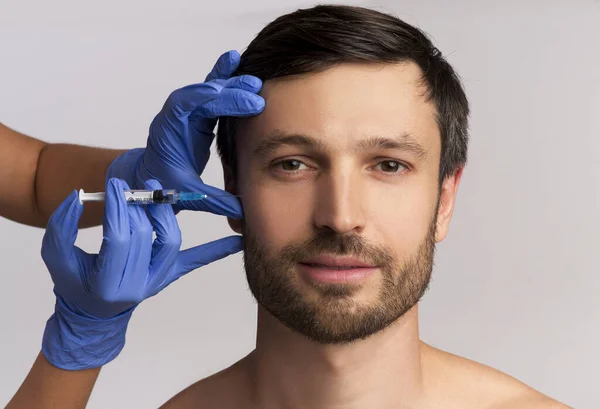 Portrét muže středního věku přijímajícího injekci proti vráskám, bílé pozadí — Stock fotografie