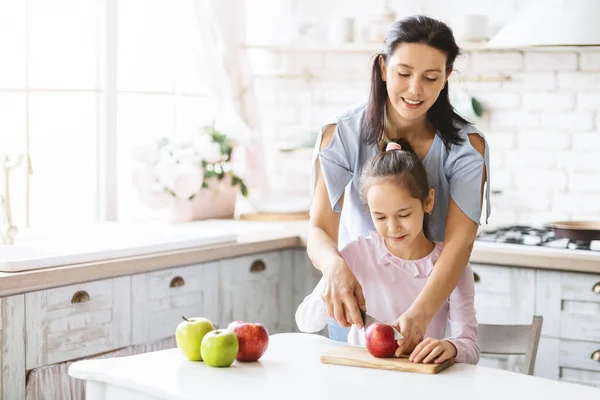 Mutter bringt ihrer kleinen Tochter bei, wie man Obstsalat macht — Stockfoto