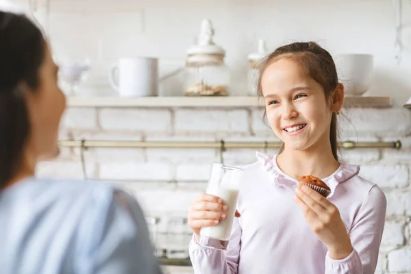 Ritratto di ragazza carina che beve latte e mangia cupcake — Foto Stock