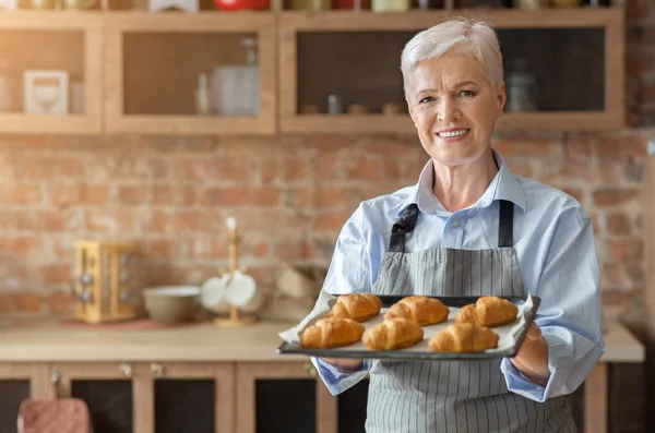 Szczęśliwa stara kobieta prezentuje tacę z self made rogaliki — Zdjęcie stockowe