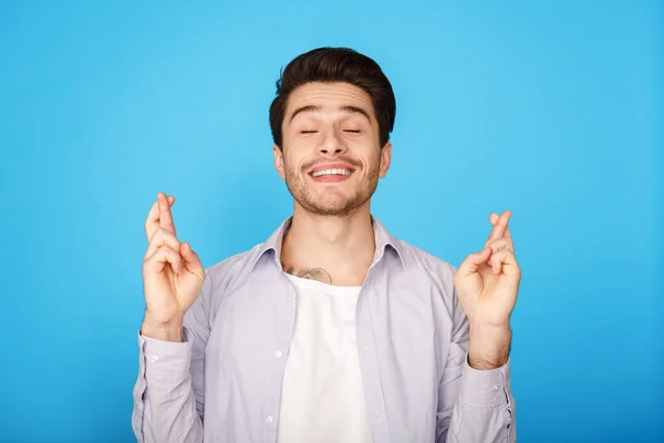 Jovem positivo cruzando os dedos, fazendo desejo — Fotografia de Stock