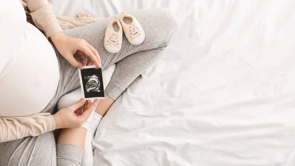Mujer embarazada disfrutando de la maternidad futura con la primera foto de ultrasonido — Foto de Stock