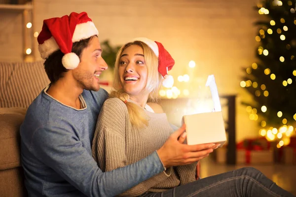 興奮したカップルオープンクリスマスギフトでリビングルーム — ストック写真