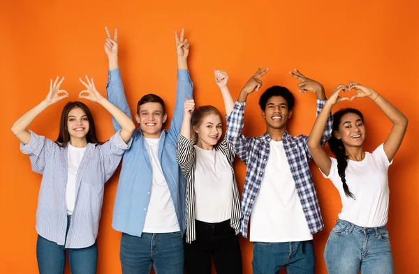 Молоді друзі жестикулюють руками над помаранчевим тлом — стокове фото