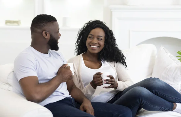 Glückliches schwarzes Paar entspannt sich auf der Couch und trinkt Kaffee — Stockfoto