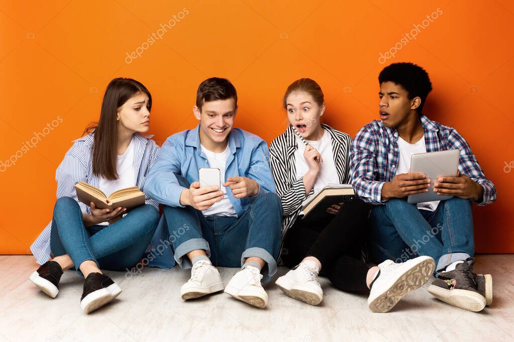 Students preparing for exams, guy showing phone