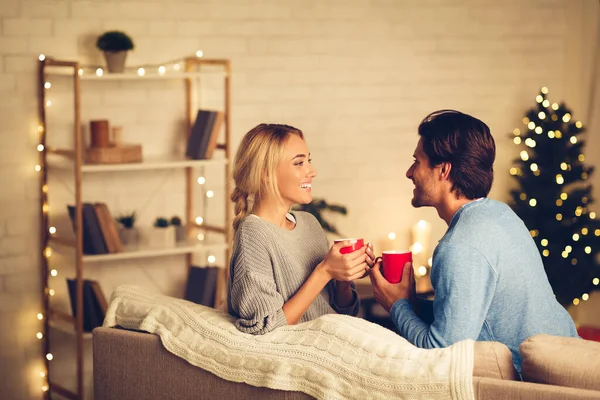 Pareja celebrando la Navidad en casa, relajándose con tazas de café —  Fotos de Stock