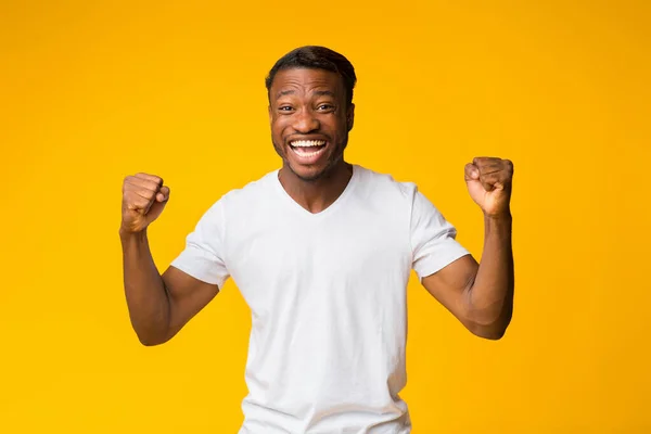 Negro chico gritando sacudiendo puños de pie sobre amarillo fondo — Foto de Stock