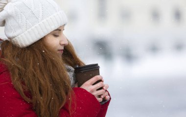 Freezing girl drinking hot coffee during walk on winter day