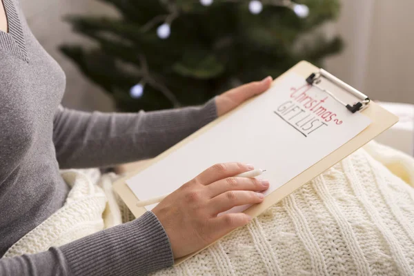 Woman under warm plaid writing Christmas gift list — Stock Photo, Image